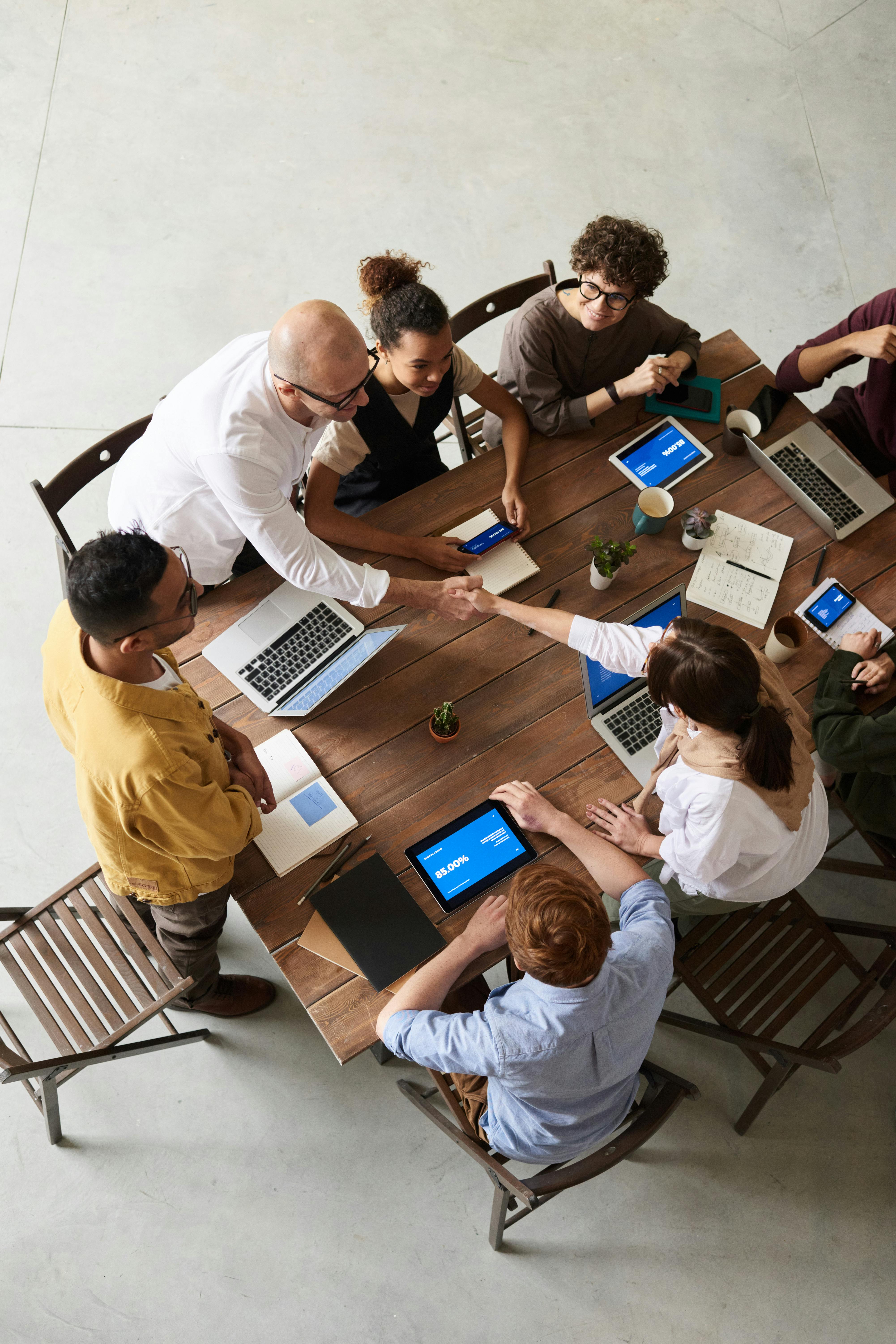 Employees around a table with a man and woman shaking hands