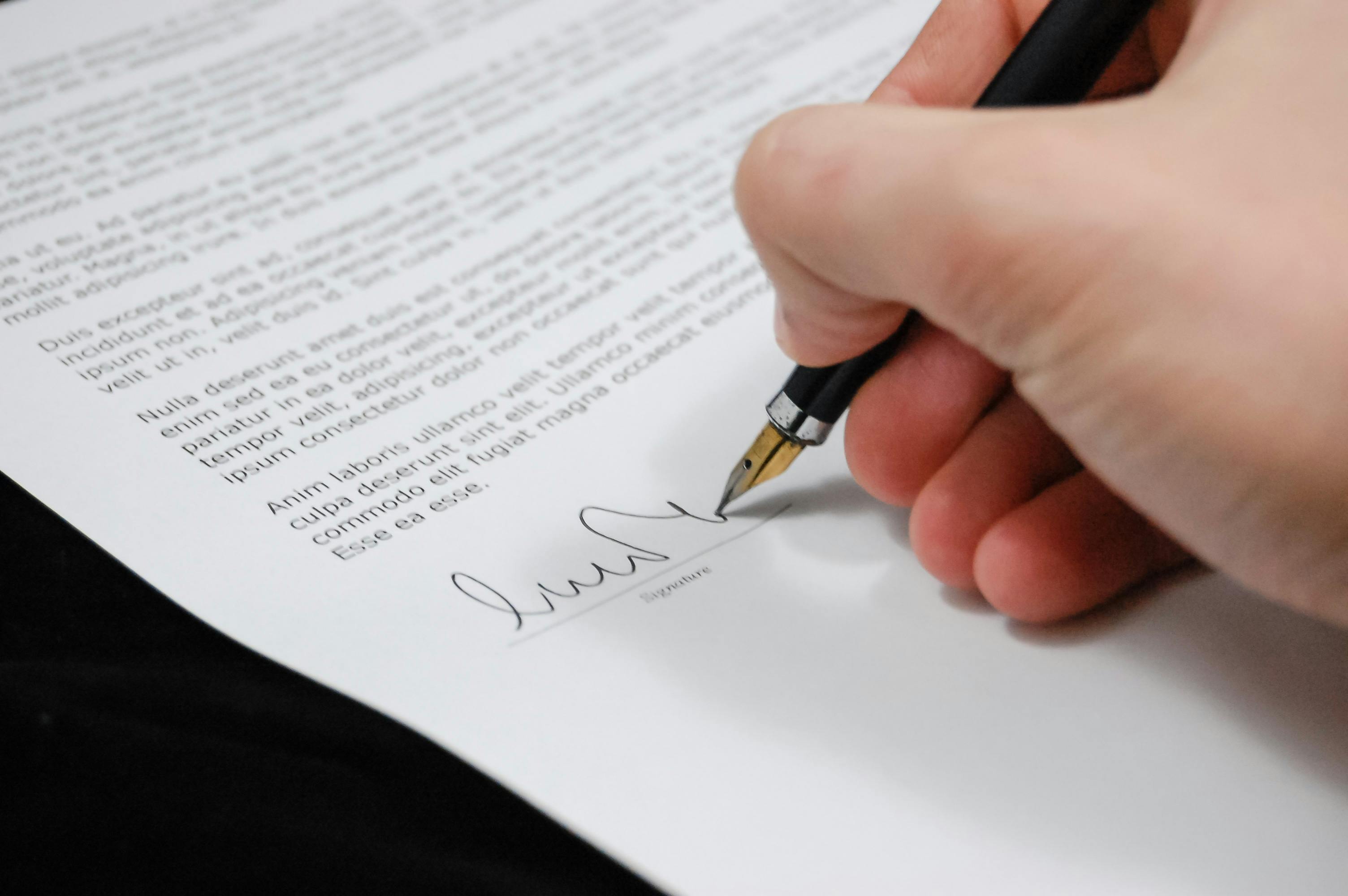 Hand signing a document with pen.