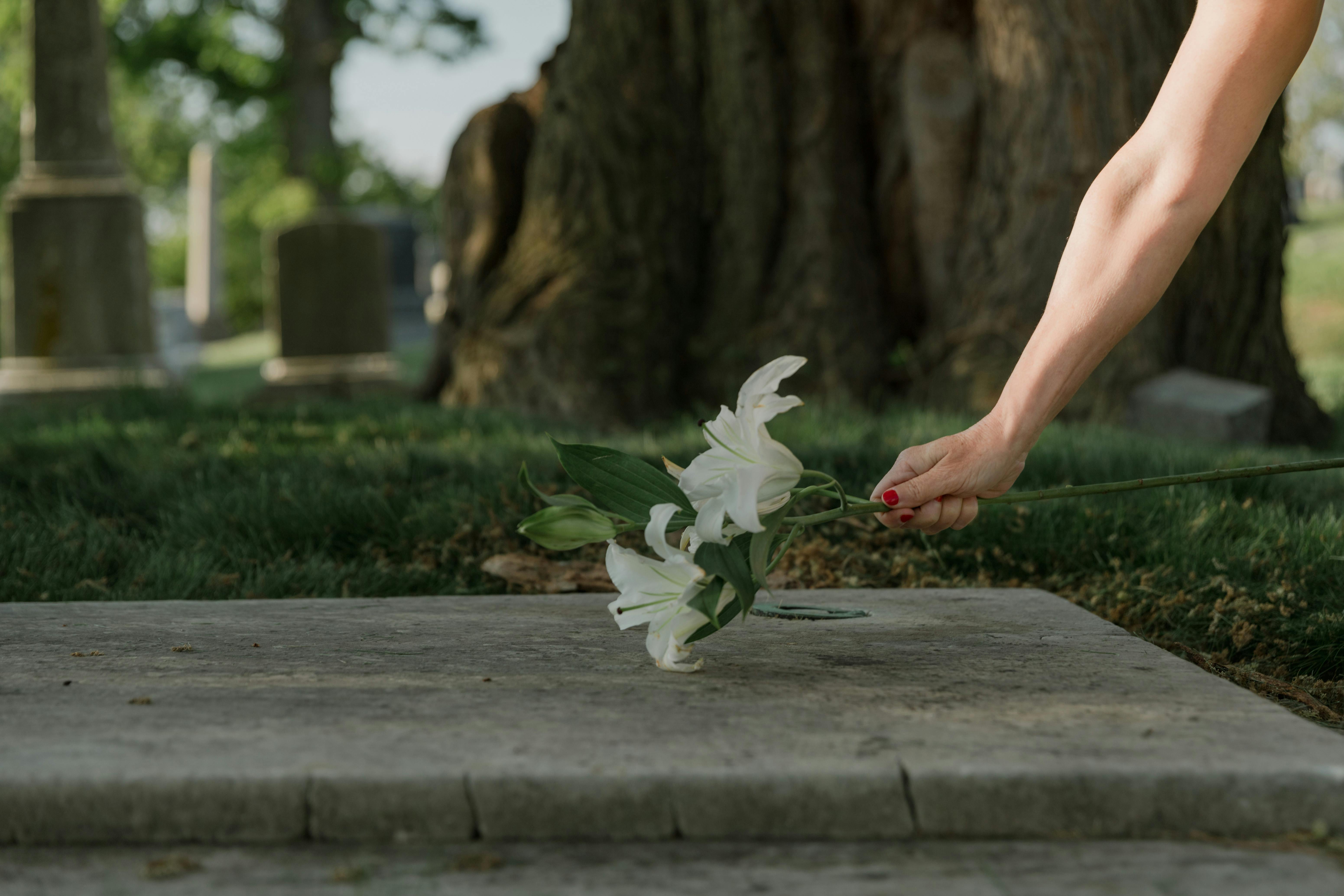 image showing arm with flowers over a grave