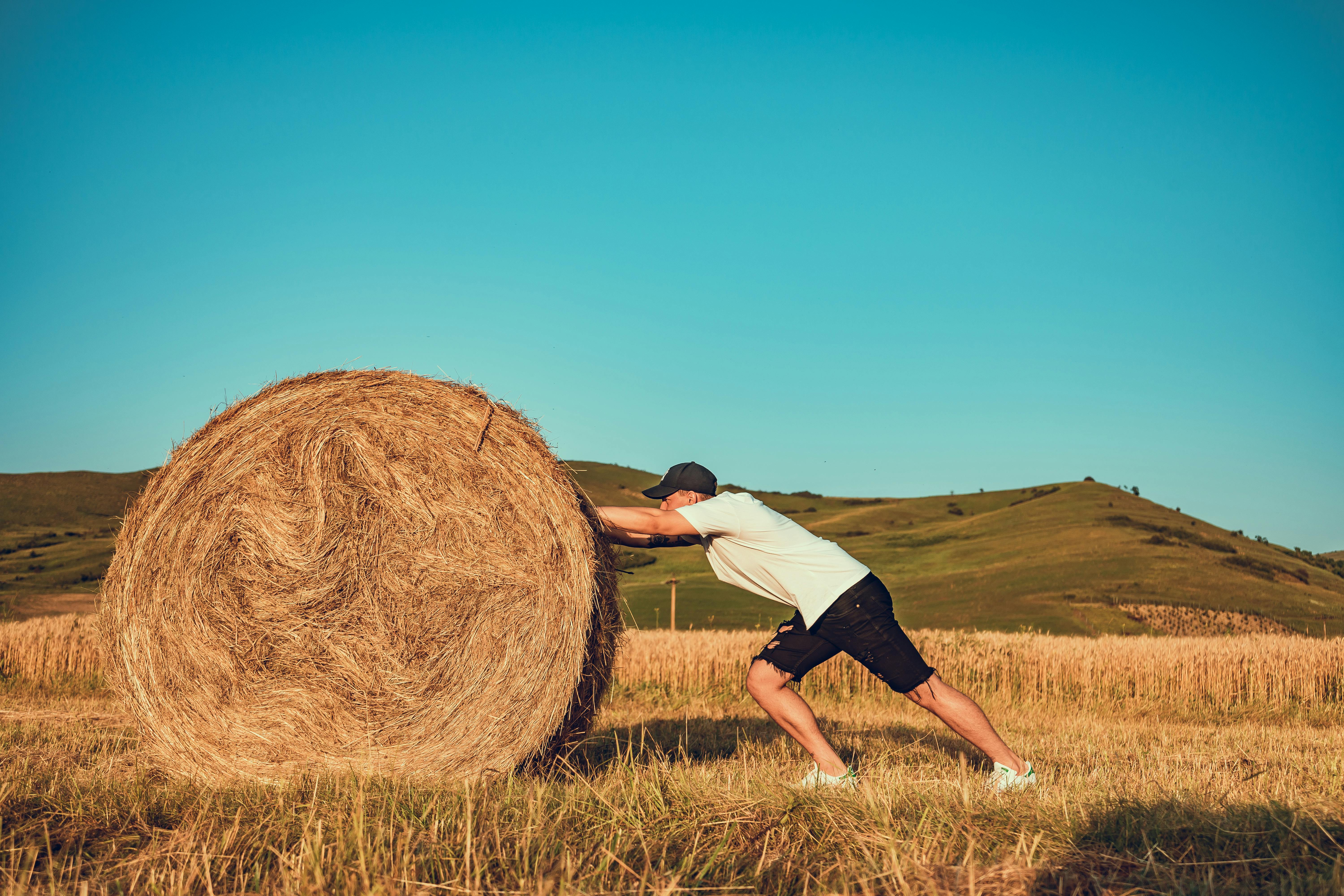 man pushing large hay bale