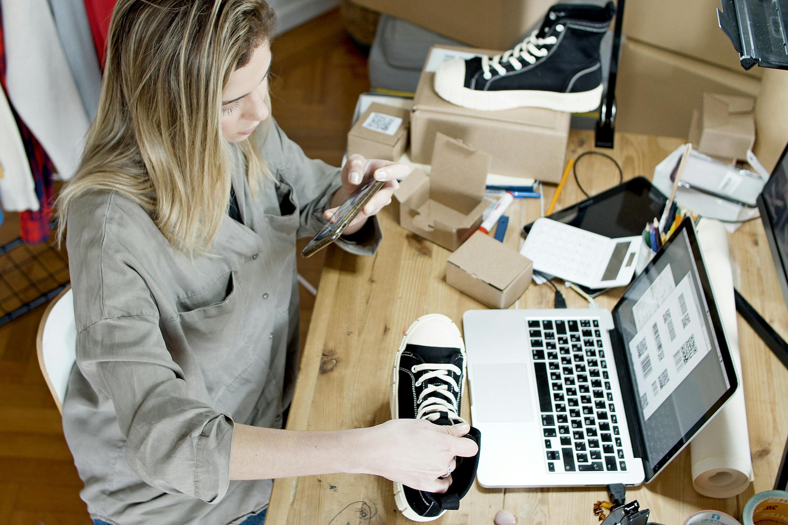 Woman with laptop and shoes, setting up for a sale