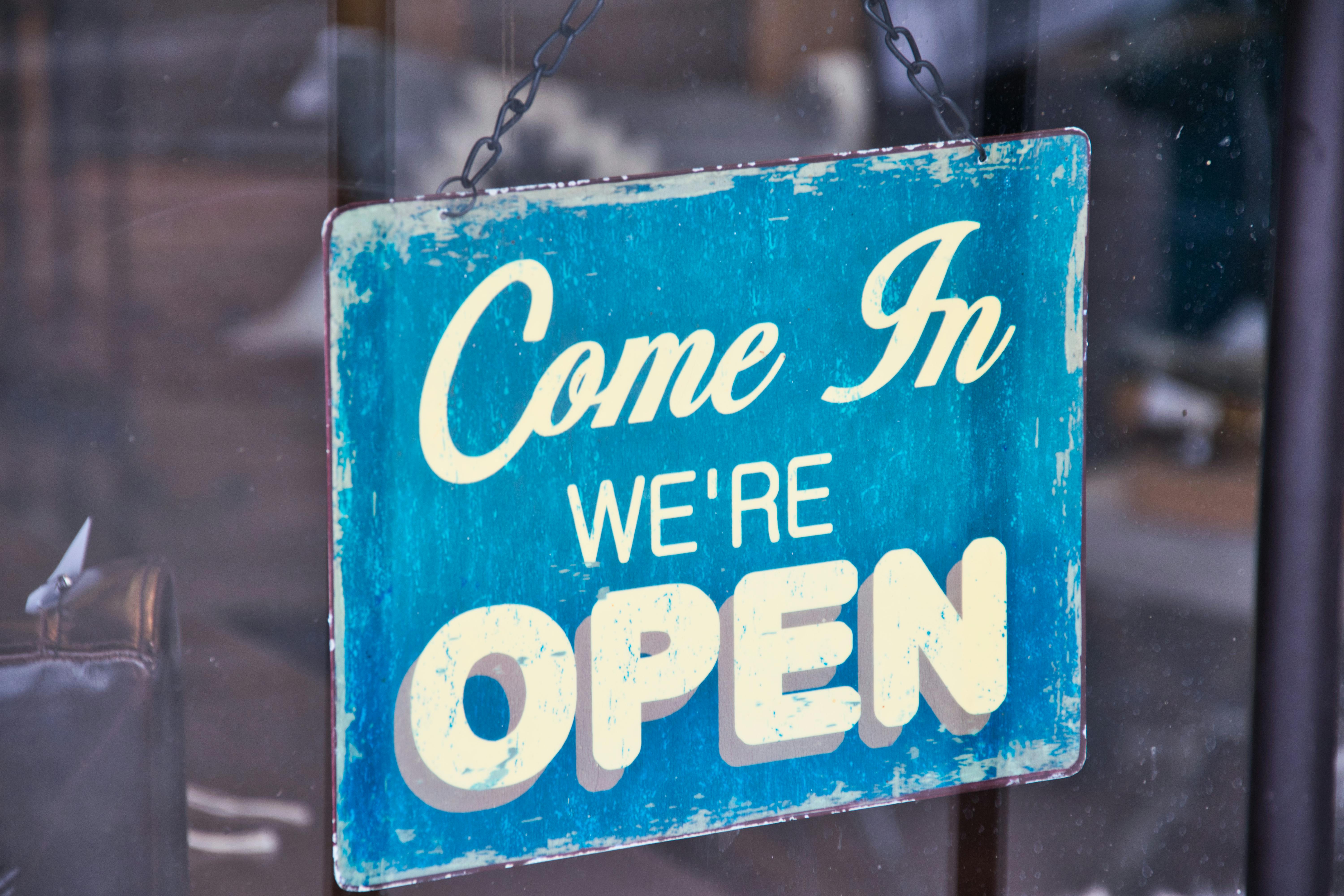 sign outside of retail store saying "come in we're open"