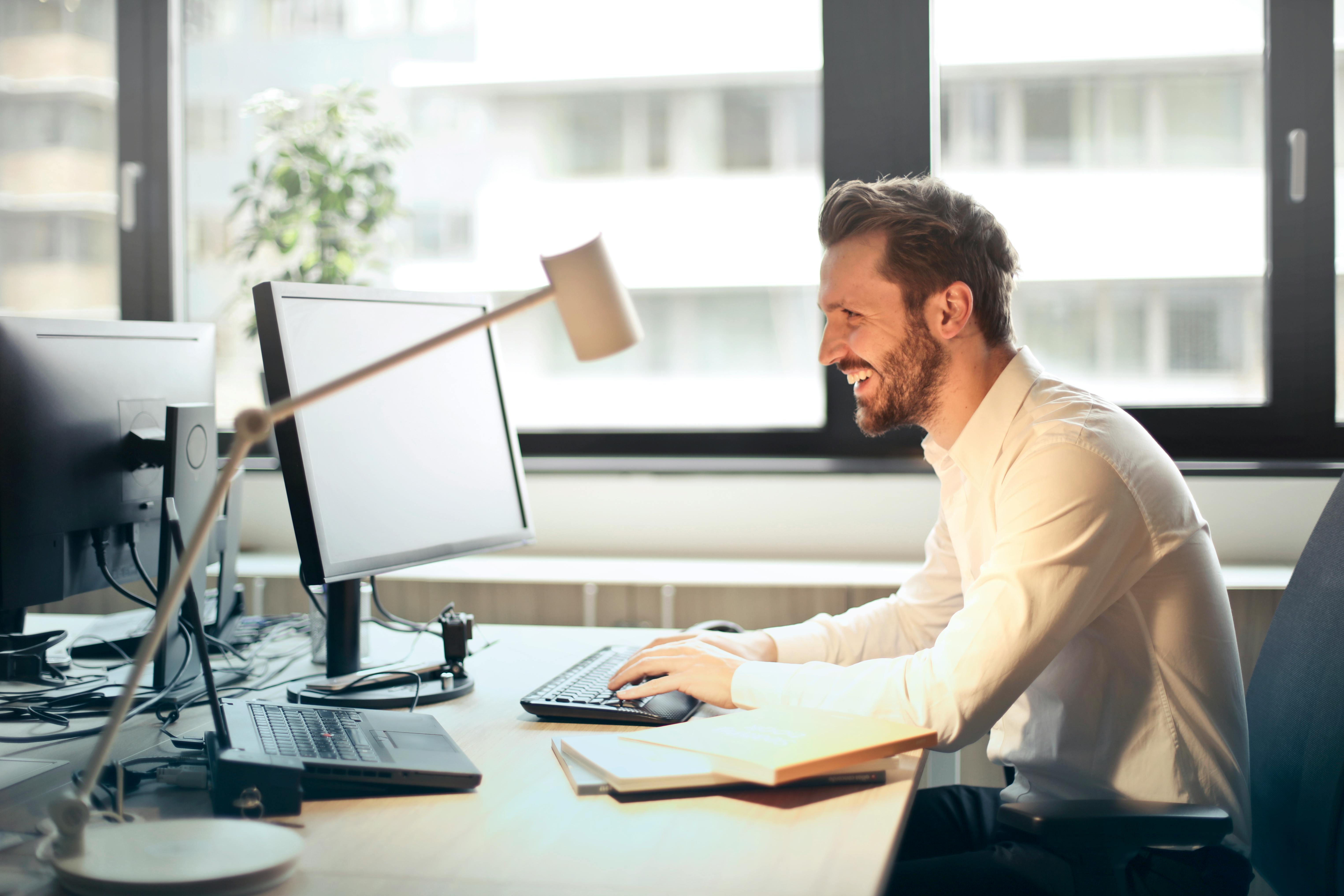 Man at desk smiling at computer monitor