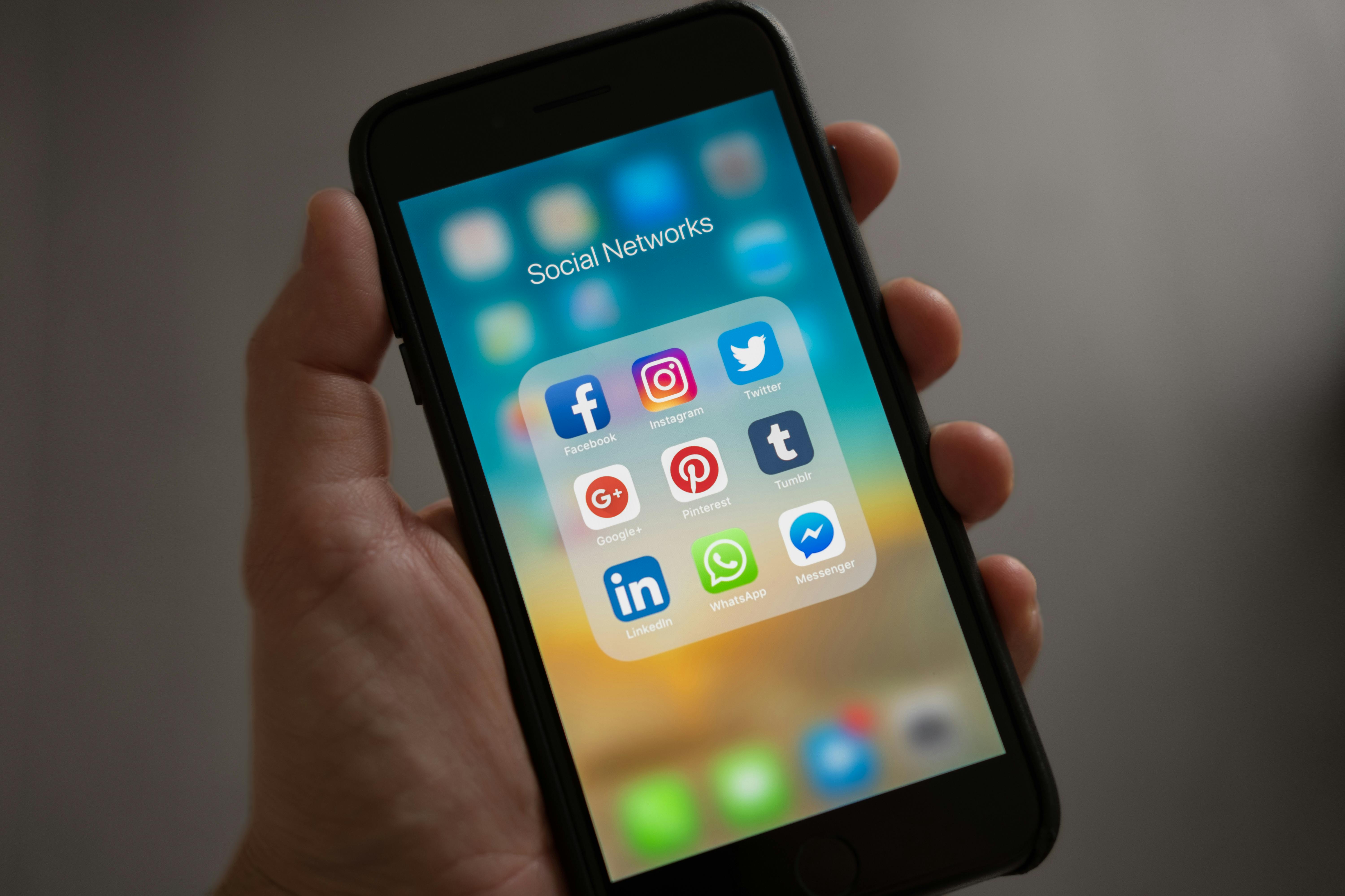 Hand holding smartphone with social apps