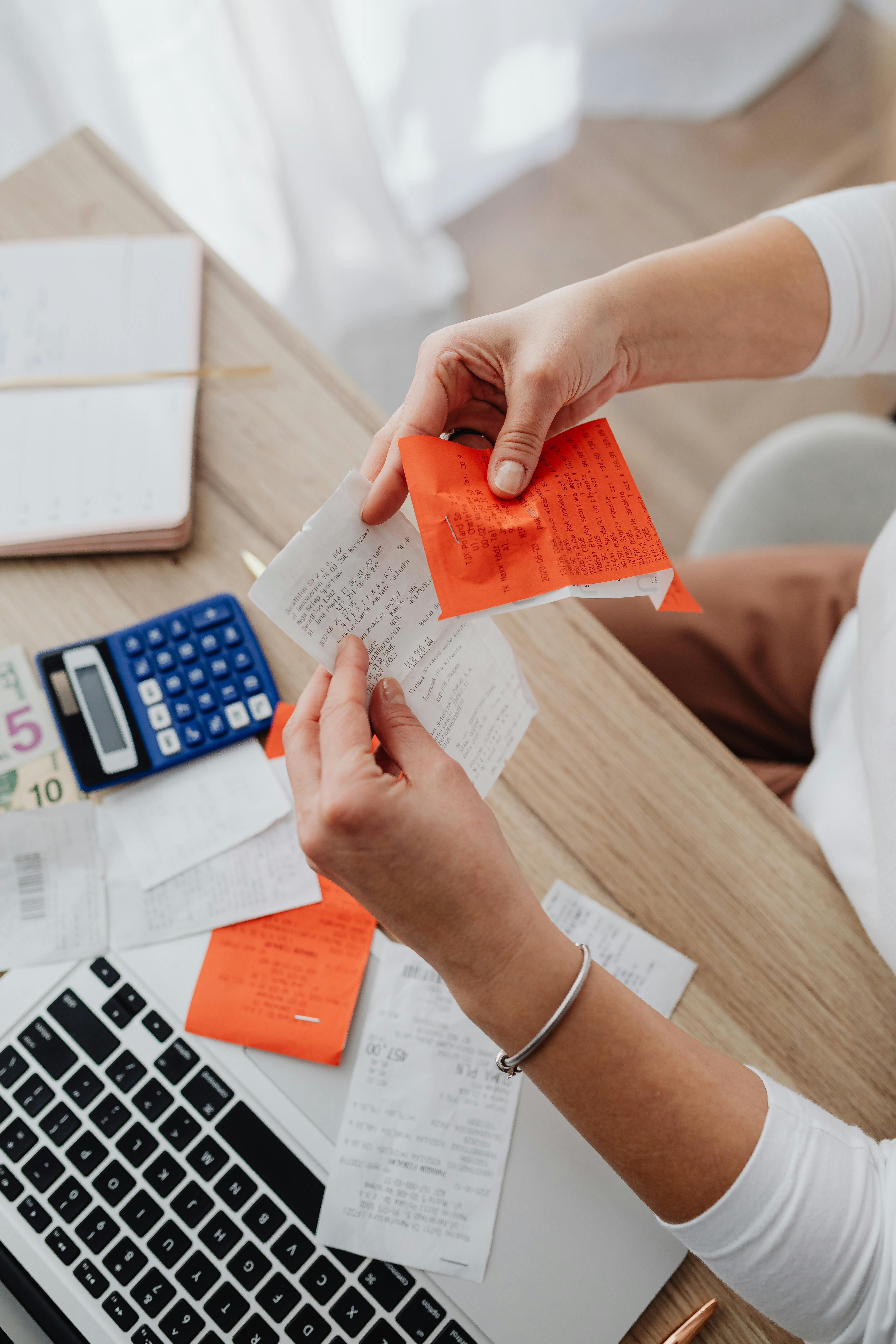Person reviewing receipts with calculator