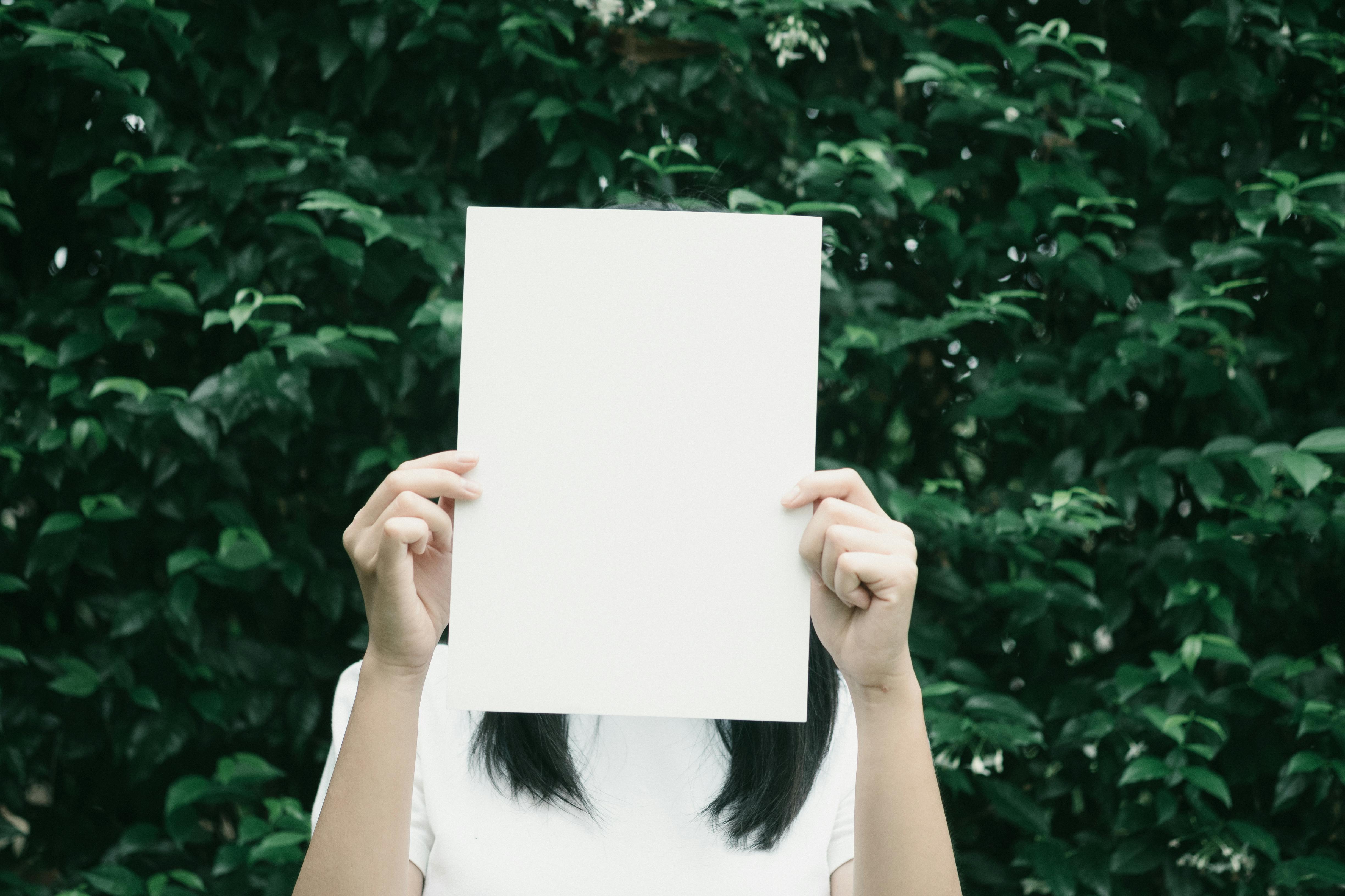 Person holding blank paper outdoors.