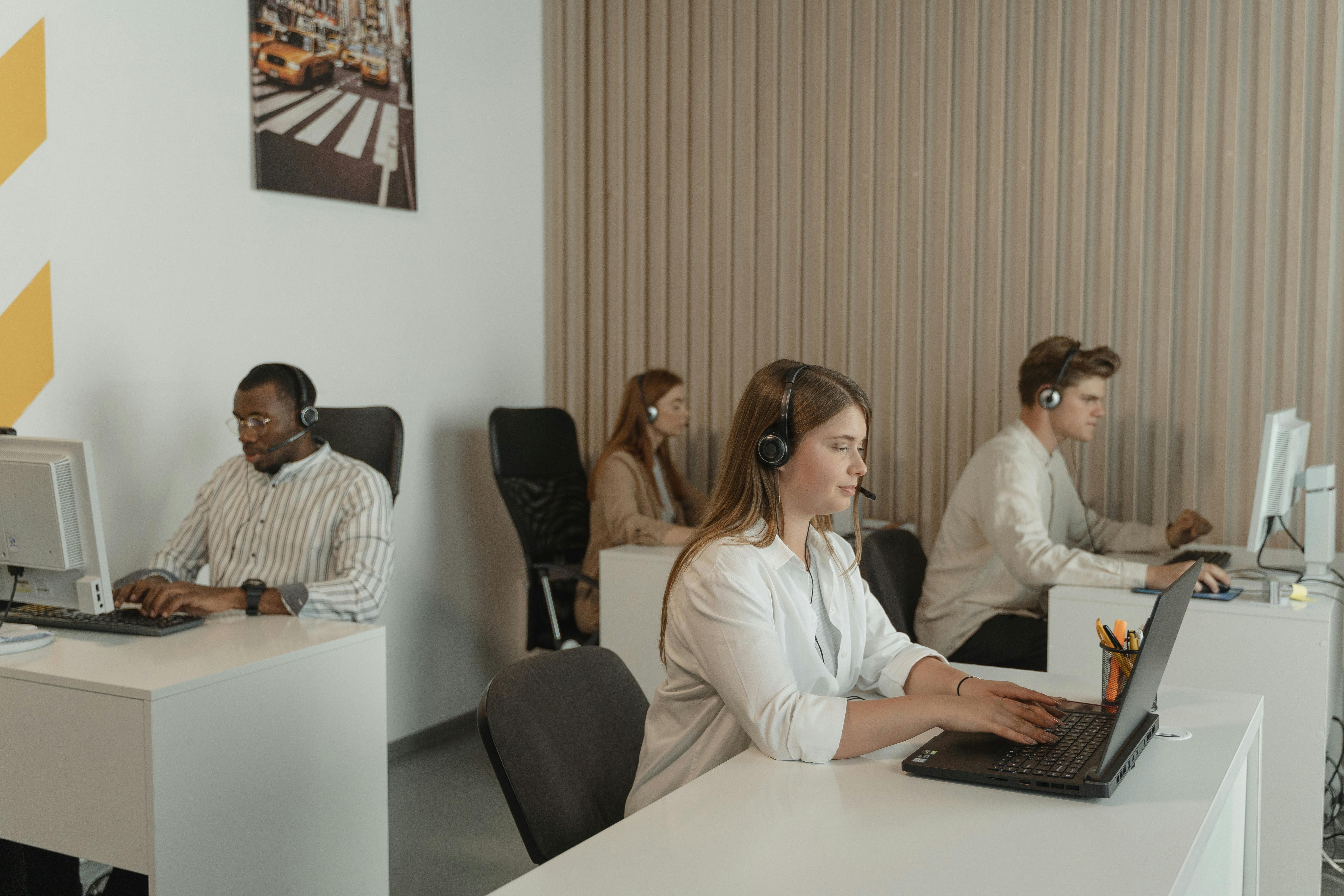 Office workers using computers and headsets.