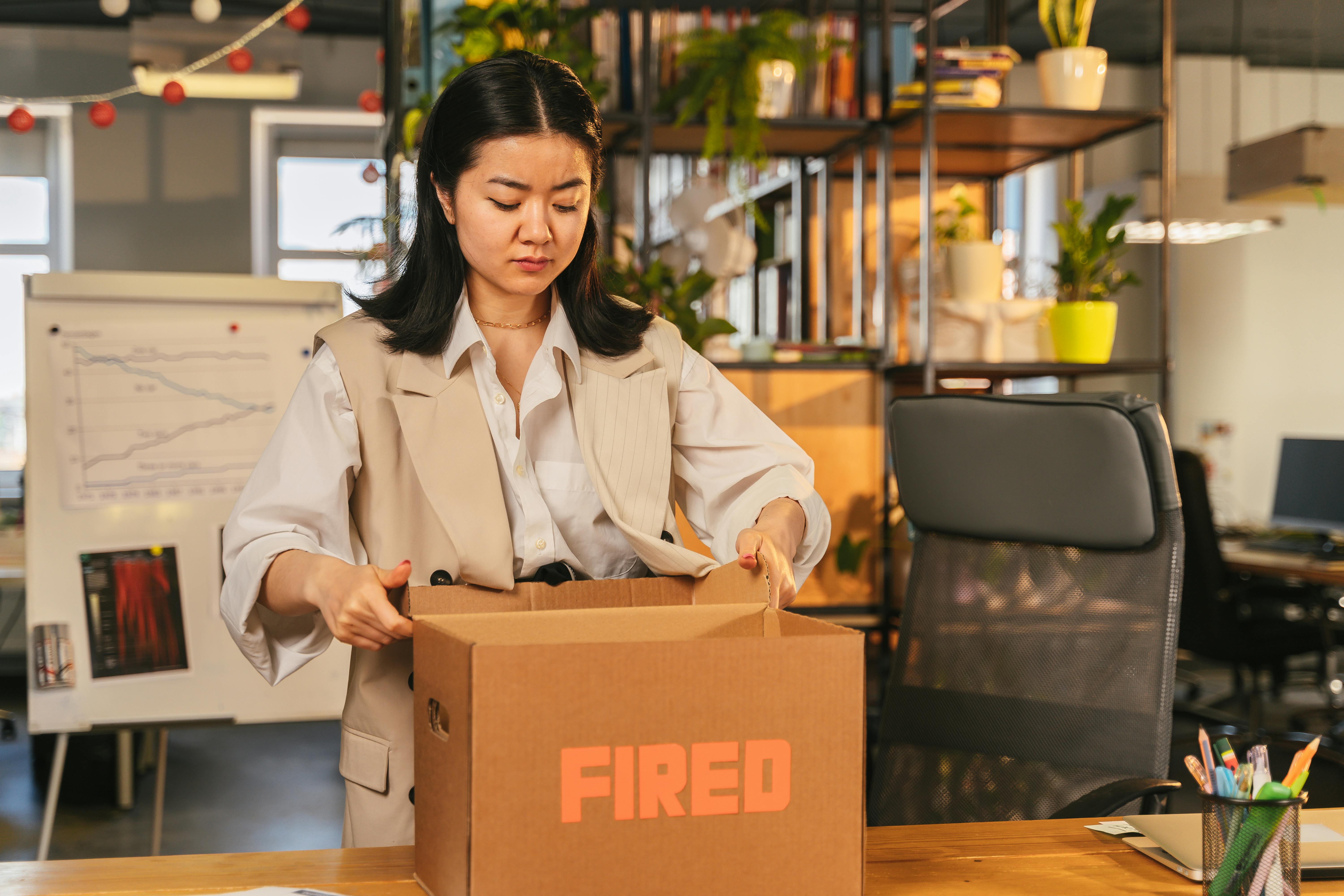 Woman with cardboard box that says "fired"